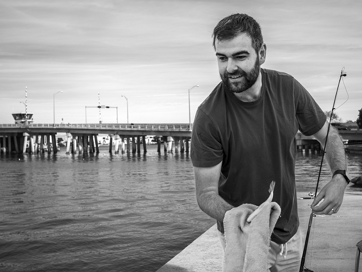 Matthew, an Australian visiting family on holiday in St. Pete Beach, prepares to return a small pinfish that he caught while fishing.